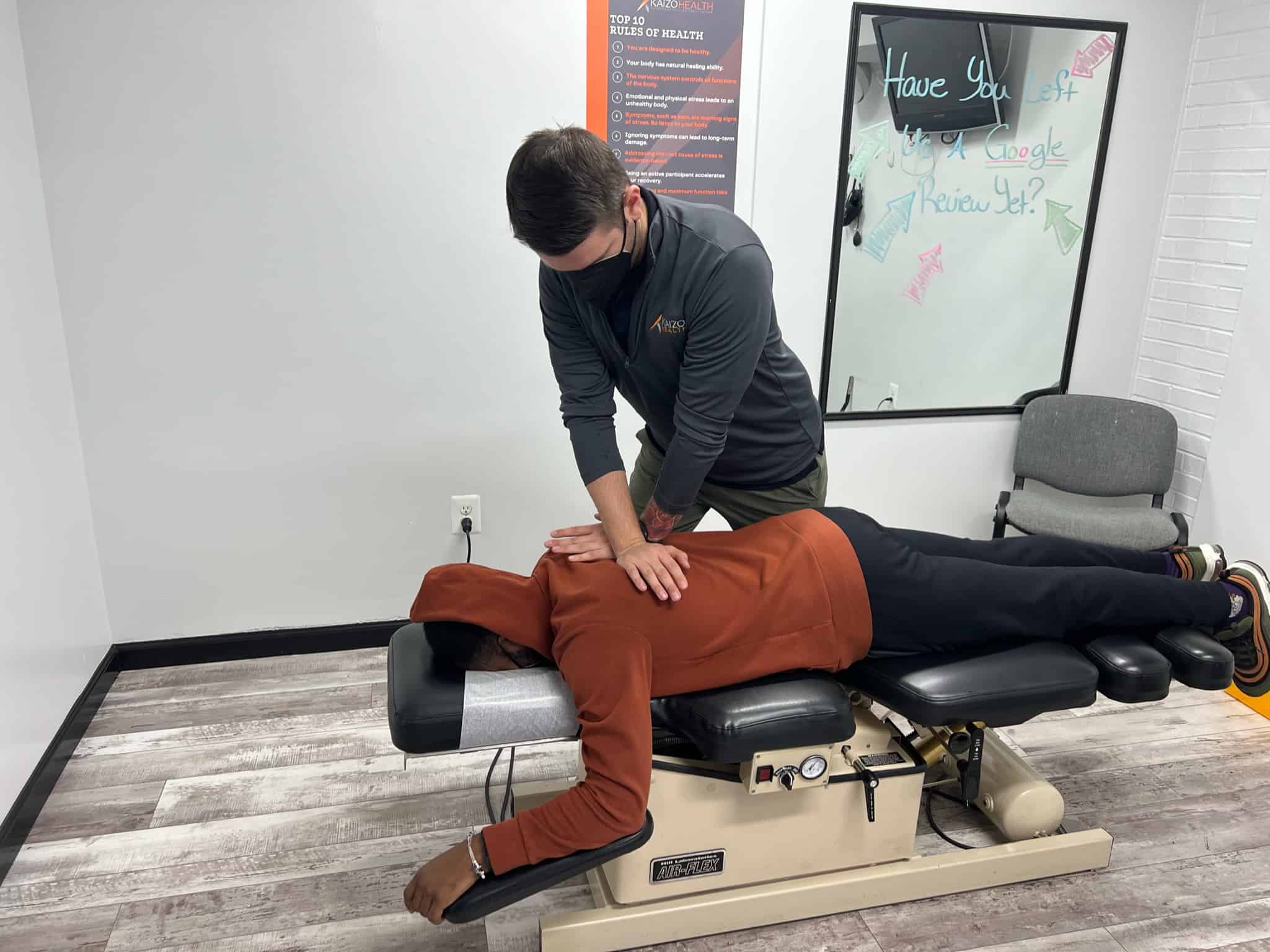 Patient lying on a chiropractic table receiving a back adjustment at Kaizo Health Fairfax.